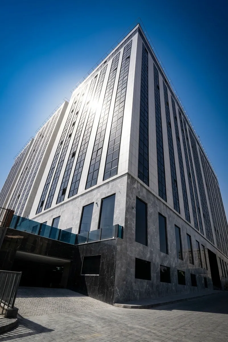 Low-angle corner view of Ronika Palace tower with black and white marble facade against the evening sky